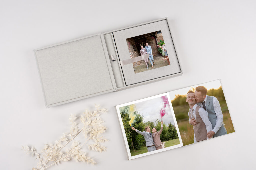 Flat lay of album, USB and prints – keepsake wedding photo collection
