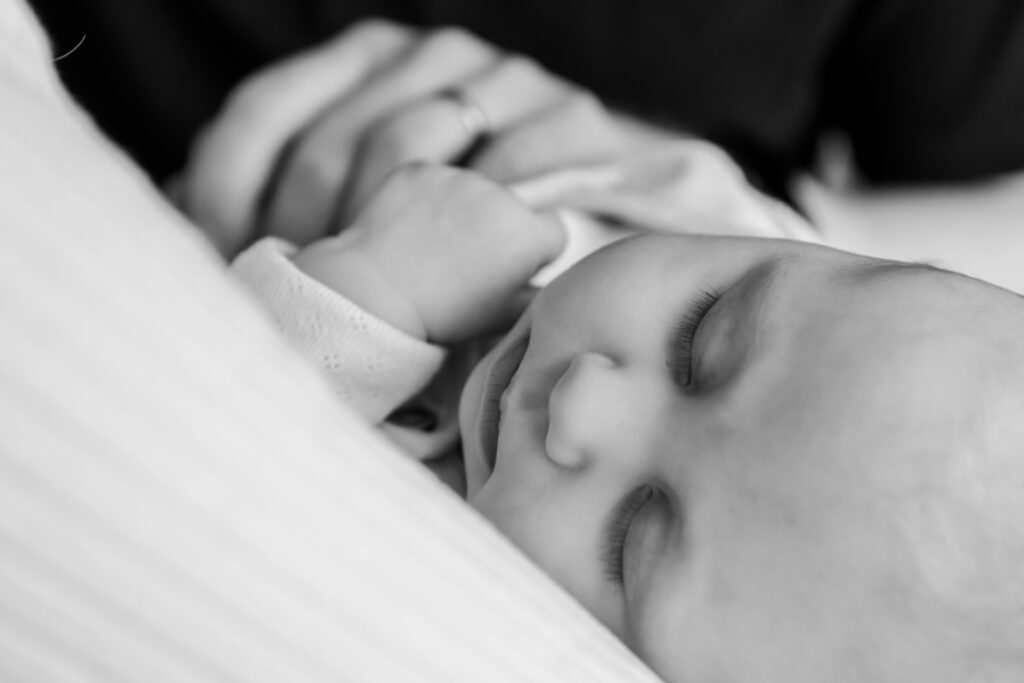 A peaceful sleeping baby resting against a soft surface, with delicate features and closed eyes.